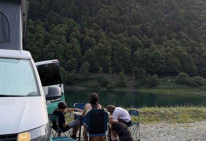 La familia de Roger sentada junto a la furgoneta al lado de un lago