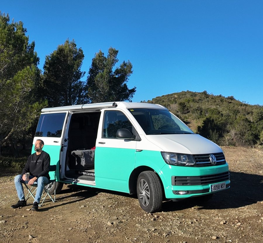 Roger sentado junto a su furgoneta camper en el monte